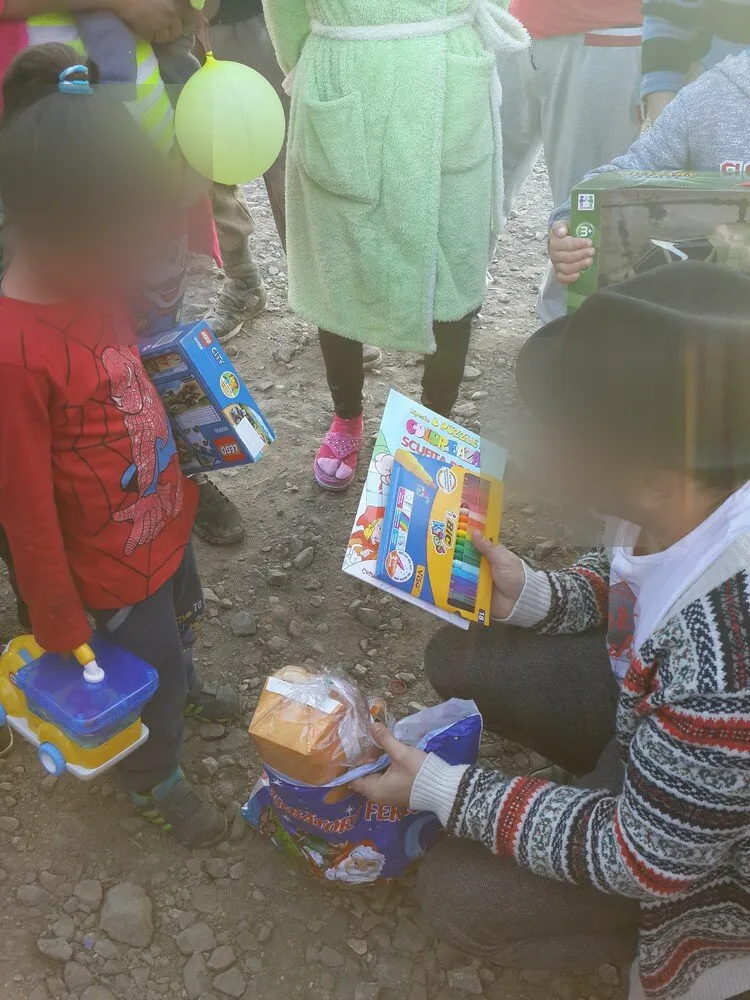 Un voluntar îi arată unei fetițe o carte de colorat și un set de carioci; fețele sunt estompate